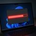 Laptop kijelzőjén piros figyelmeztető sáv egy hiba vagy figyelmeztetés szimbóluma jelenik meg.